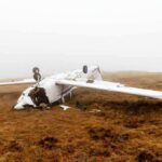 Overturned crashed airplane on grassy field.