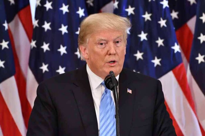 1191272242 featured image Man speaking at podium with American flags behind