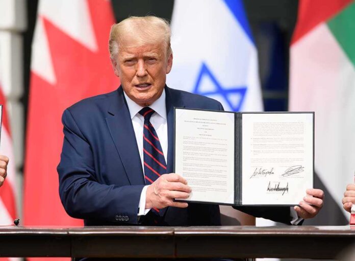 1816392461 featured image Man holding signed document with three visible flags