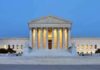 Large neoclassical building with illuminated columns at dusk