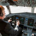 Pilot in cockpit operating airplane controls.