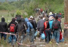 People walking on a path carrying bags outdoors
