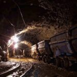 Dimly lit mine shaft with rail carts and tracks.