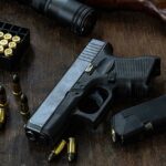 Handgun with ammunition magazine and rifle on wooden table