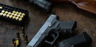 Handgun with ammunition magazine and rifle on wooden table