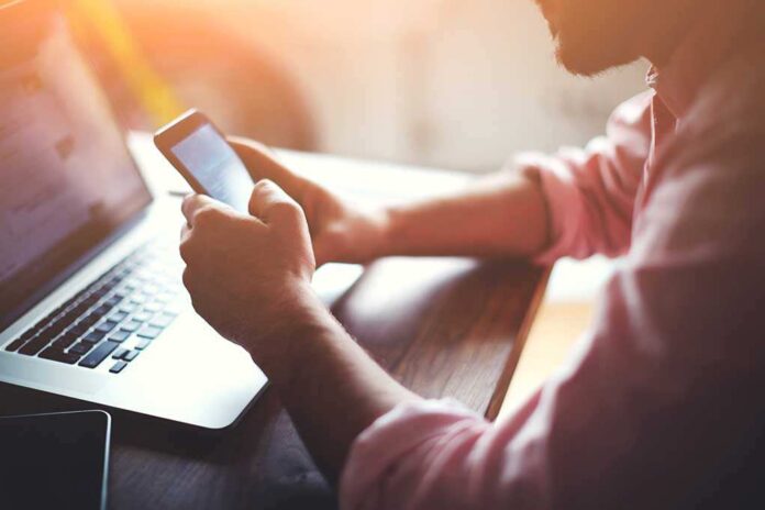 268450493 featured image Person using a smartphone and laptop at desk