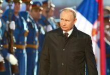 A man in dark coat at a military event
