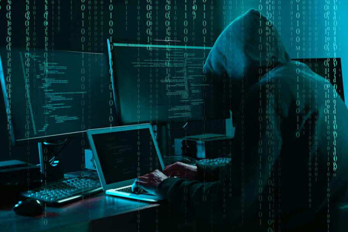 1703023243 Hacker in dark room surrounded by computer screens