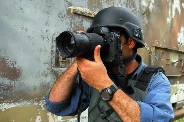 Person in helmet taking photos with a large camera
