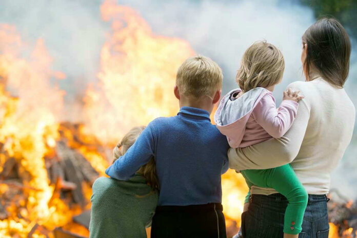 220431301 Three children and adult watching large fire outdoors
