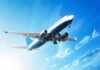 An airplane flying against a clear blue sky with clouds