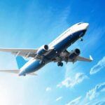 An airplane flying against a clear blue sky with clouds