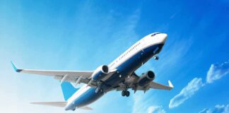 An airplane flying against a clear blue sky with clouds