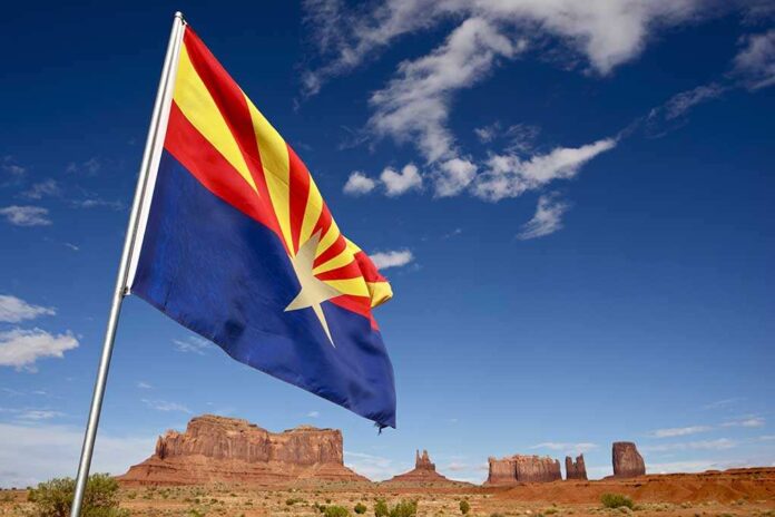 shutterstock_141731293.jpg Arizona state flag waving in front of Monument Valley under a blue sky