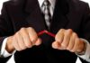 Businessman in a suit breaking a pencil with his hands