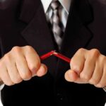 Businessman in a suit breaking a pencil with his hands