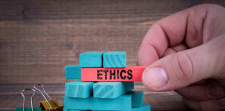 Hand holding red block labeled "ETHICS" above blue blocks.
