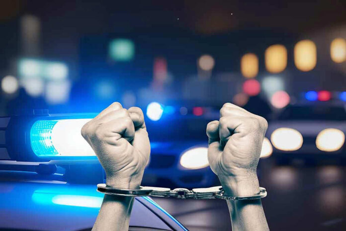 Hands in handcuffs in front of police cars