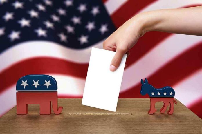 A hand placing a ballot into a box with political symbols on either side against a backdrop of the American flag