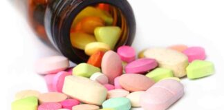 A variety of colorful pills and tablets spilled from a brown medicine bottle