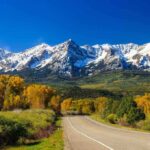 Cartel Wasteland DESTROYS America’s Sacred Park Scenic view of snow-capped mountains with autumn trees and a winding road