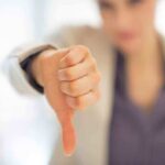 Go Woke Go Broke: New Victim Falls After 48 Years… Businesswoman showing a thumbs down gesture in an office setting