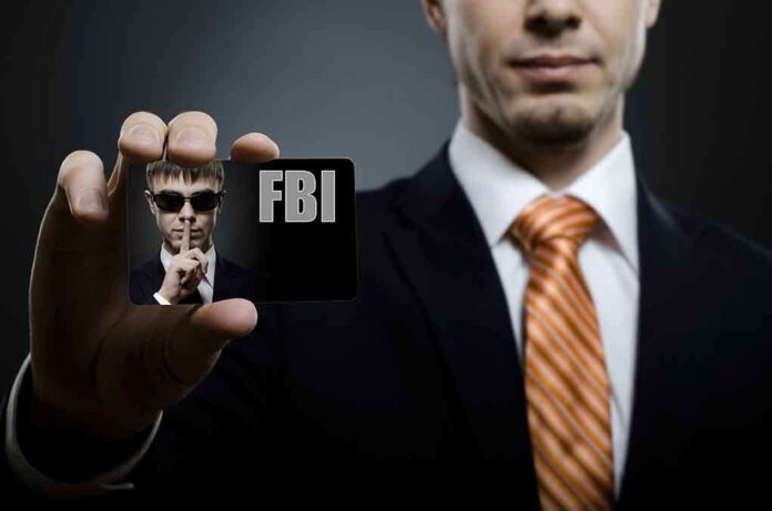 A man in a suit holding an FBI identification card while making a shushing gesture