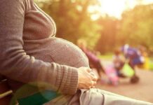 Pregnant woman sitting on a bench in a park during sunset