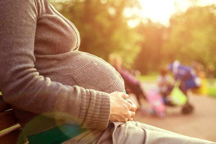 shutterstock_150533705.jpg Pregnant woman sitting on a bench in a park during sunset