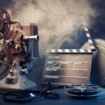 A vintage film projector with film reels and a clapperboard surrounded by smoke