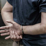 Person in handcuffs with hands behind back.