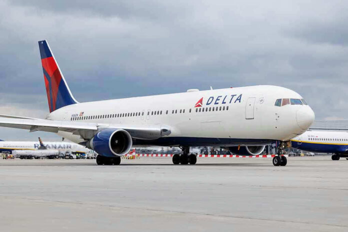 2305553471 Delta Airlines airplane on airport runway, cloudy sky.
