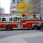 Red fire truck driving through city street crosswalk