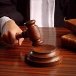 Conservatives Outraged — 8 Years for ASSASSINATION PLOT! A judges hand holding a gavel over a wooden desk with law books