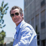 Man in sunglasses wearing a blue button-up shirt.