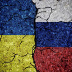 Cracked Ukrainian and Russian flags painted on concrete.