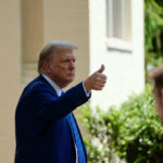 Man in suit giving thumbs up.