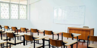 Empty classroom with desks, chairs, and whiteboard.