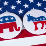 Campaign Bus Inferno—Governors Race In Chaos! Republican elephant and Democrat donkey on American flag.