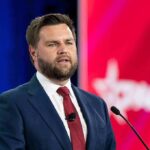 Vance CALLS OUT GOP Rebel – He’s Done A man in a suit speaking at a podium during a conference