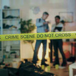 Crime scene with tape and investigators examining evidence.