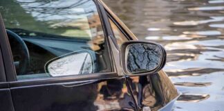 A partially submerged black car in floodwaters