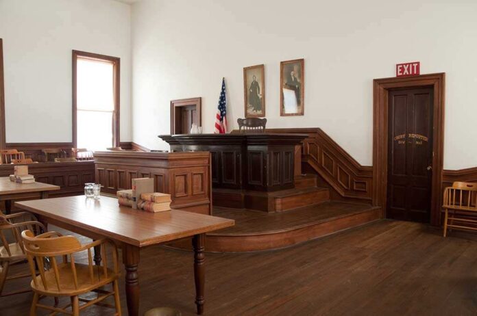 Interior of a historic courtroom with wooden furniture and an American flag