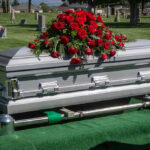 Silver casket with rose bouquet in a cemetery.