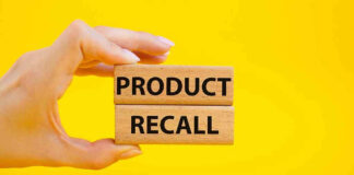 Hand holding Product Recall blocks on yellow background.