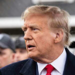 TRUMP Threatens Military Against American Citizens Man in suit and red tie speaking outside.