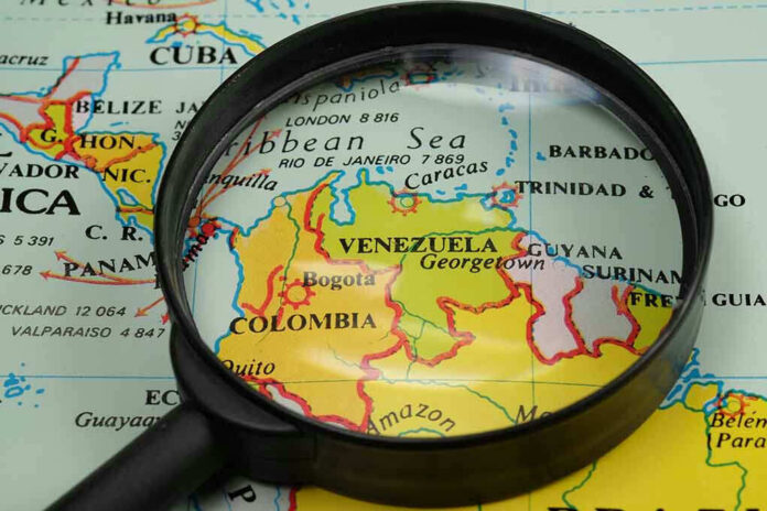 435064315 Magnifying glass focusing on Venezuela and Colombia on map.