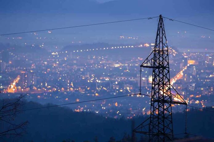 Night view of a city skyline with power lines in the foreground
