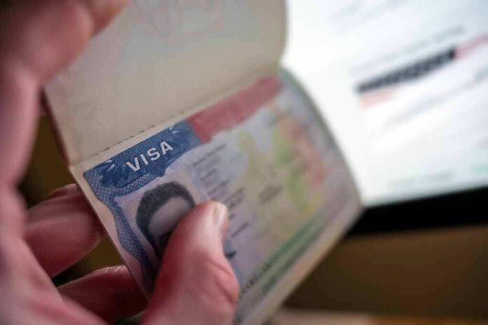 A hand holding an open passport displaying a visa page