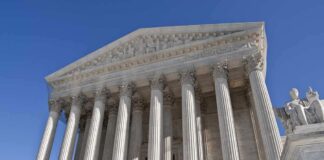 The Supreme Court building featuring grand columns and statues under a clear blue sky